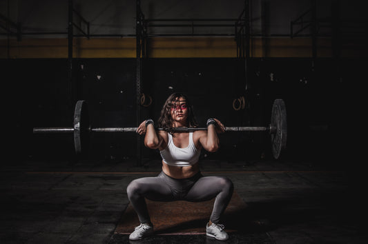 An athlete (athletic woman) lifting a heavy weight and working out (specifically squatting)