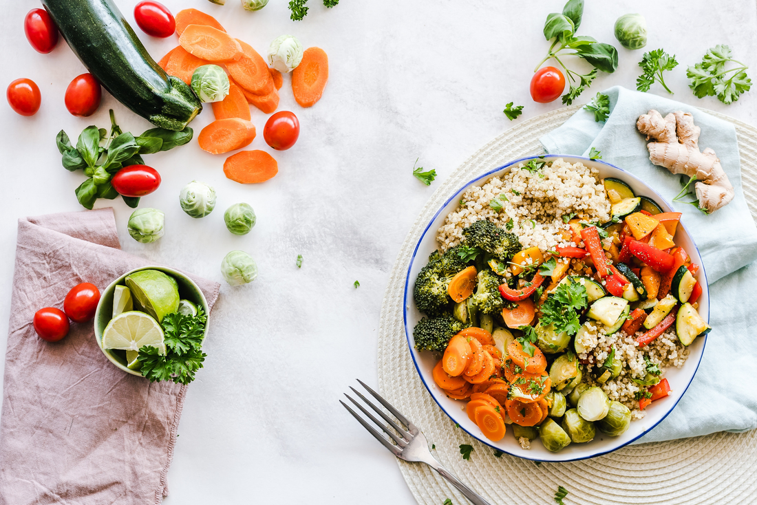 Grain bowl with lots of fruits (tomatoes, limes, zucchini) and vegetables (carrots, brussel sprouts, cilantro)