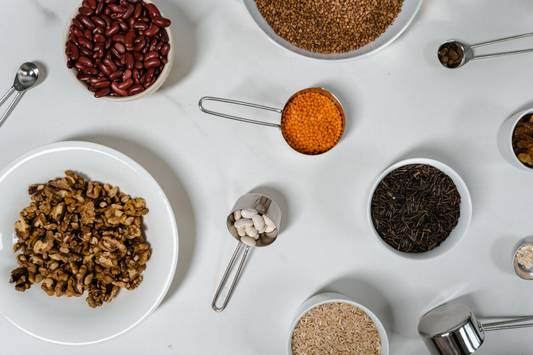 Servings of spices (chili pepper, paprika), nuts (walnuts), beans (kidney beans, red beans), grain, and seeds