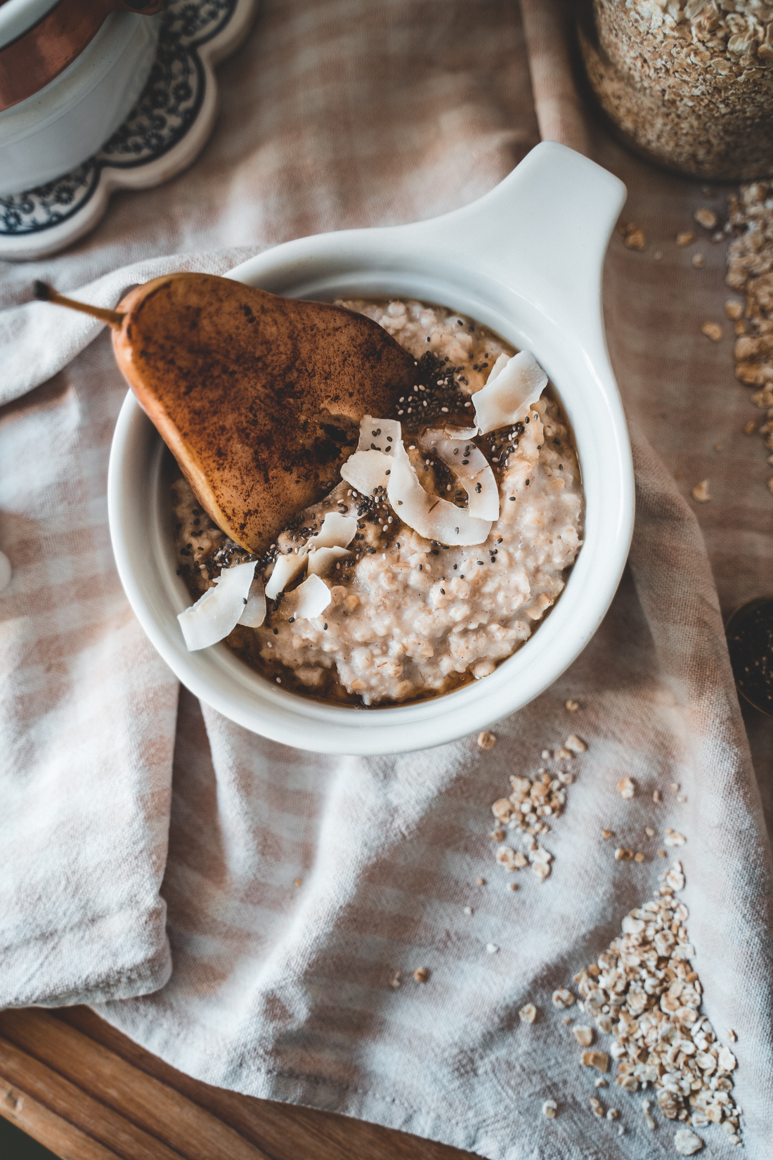 Bowl of oatmeal with chia seeds, flax seeds, pear, almonds, nuts, and coconut chips