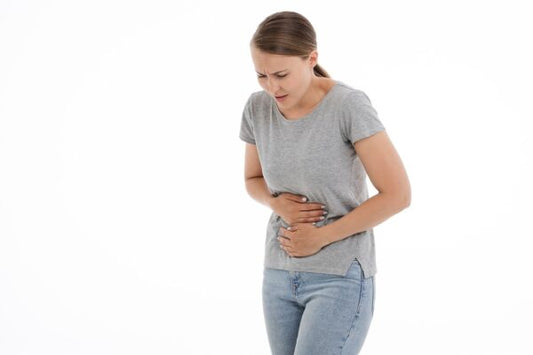 Woman clutching her stomach due to stomach pains that include bloating