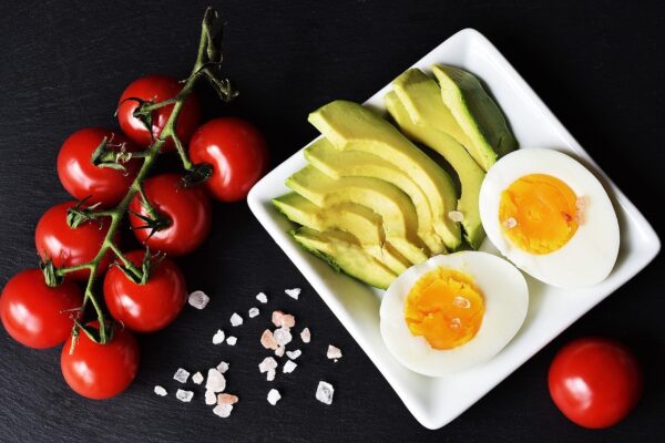 Table of a variety of foods (tomatoes, avocado, salt, eggs) to showcase the keto diet