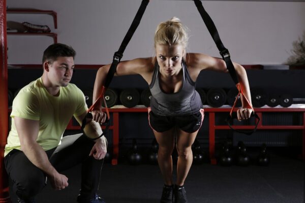 Woman working out her arms and exercising with a male trainer at the gym