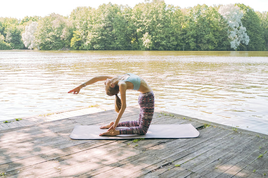 Woman exercising and doing yoga on a deck in front of a lake