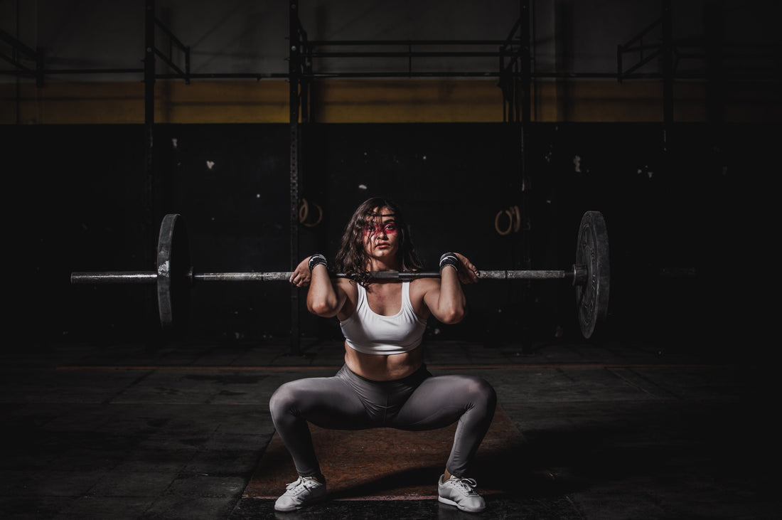 An athlete (athletic woman) lifting a heavy weight and working out (specifically squatting)
