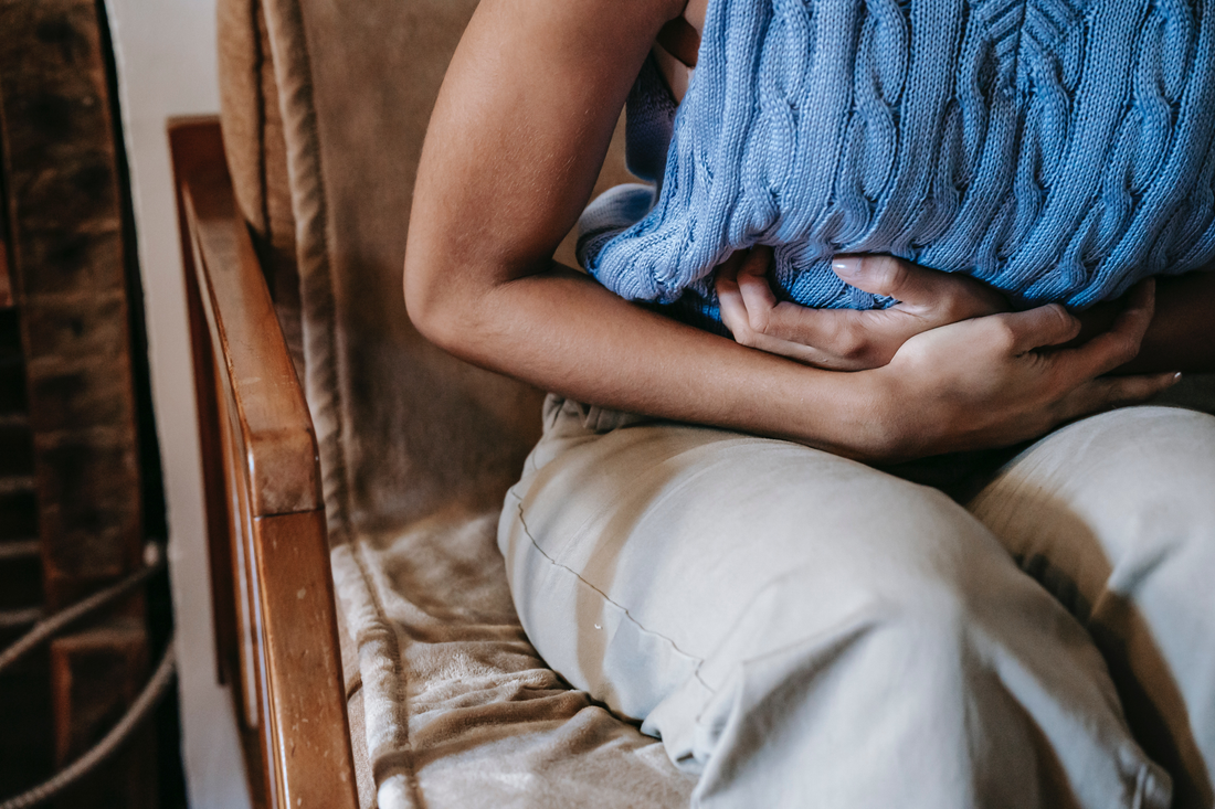 Person clutching their stomach due to stomach issues related to SIBO (stomach intestinal bacterial overgrowth)